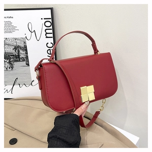 Détail d'un sac à main bordeaux en cuir élégant avec un fermoir rotatif carré doré