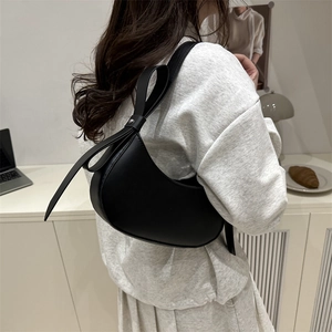 Minimalist black crescent hobo bag with ribbon knot detail on shoulder strap for women
