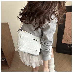 Close-up of white crossbody bag featuring wrinkled nylon fabric and circular brand logo