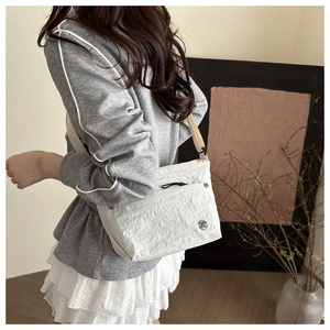 Detailed shot of white pleated nylon crossbody bag with black zipper pocket and M logo