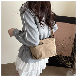 Khaki nylon crossbody bag shown from the back on a casual outfit with metal logo