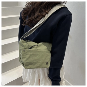 Close-up of green nylon crossbody bag with zipper pocket and adjustable strap