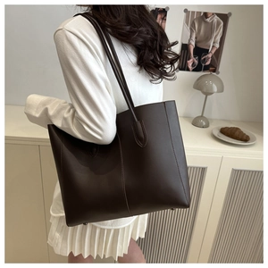 Detail of dark brown leather tote bag with sturdy straps and neat stitching on shoulder