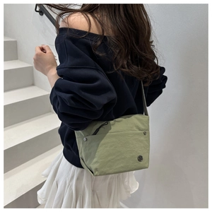 Close-up of lightweight light green nylon shoulder bag with zip pocket and adjustable strap