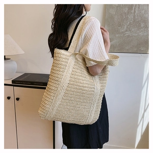 Detailed close-up of ivory woven straw beach tote bag with hollow knit patterns and dual straps