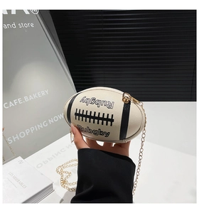 Detailed macro view of the cream rugby-shaped mini bag showing faux leather texture and chain