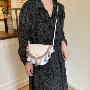 Ethnic straw woven crossbody bag with colorful tassels and embroidery on creamy white fabric