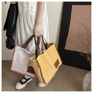 Detail of corduroy tote bags in cream and yellow showing texture and leather label