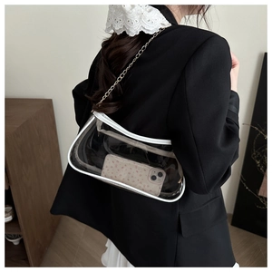 Detailed side view of clear PVC underarm bag with white leather trim and gold chain
