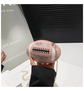 Close-up of pink rugby shaped handbag with gold chain strap and letter embossing