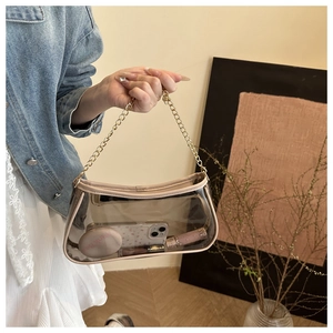 Detail of transparent PVC underarm bag featuring a stylish gold metal chain strap