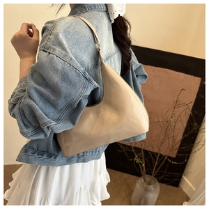 Detail view of a beige patent leather hobo shoulder bag styled with a casual outfit