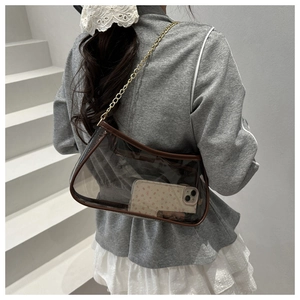 Close-up of clear PVC crossbody bag with brown leather trim and gold chain strap
