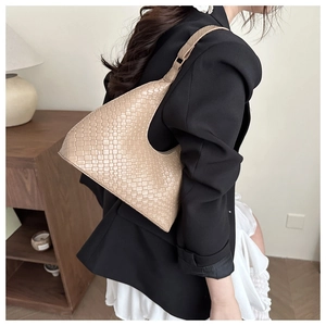 Detail of beige woven leather shoulder bag showing intricate texture and crescent design