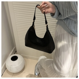 Detail of black woven crescent hobo bag with gold zipper and minimalist texture