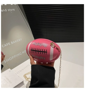 Detail of pink rugby-shaped handbag with chain strap and Rubgby lettering print