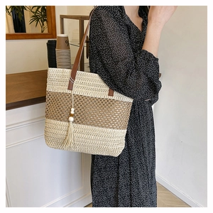Detail of handwoven hollow patchwork tote with brown leather straps and tassel charm