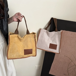 Fashionable corduroy tote bag in yellow and off-white with brown straps and logo