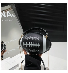 Detail of rugby-shaped black leather bag with gold chain and white varsity lettering