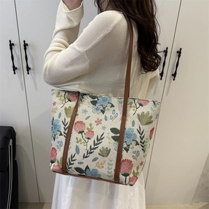 Floral canvas tote bag with brown leather straps shown on shoulder for daily commute