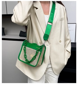 Detail of green leather and straw woven crossbody bag with chunky chain and fabric strap