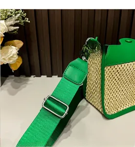 Detail of woven straw shoulder bag featuring green leather trim and adjustable wide strap
