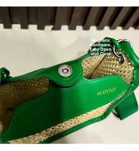 Detail of green leather flap and silver magnetic clasp on woven straw crossbody bag