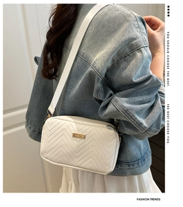 Detail of white quilted crossbody bag with golden plaque and wide adjustable strap