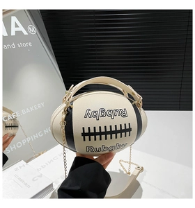 Detail of rugby-shaped cream crossbody bag with black stripes and metal chain strap