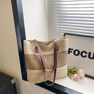 Hollow straw shoulder bag with tassels and leather straps in a chic beach style