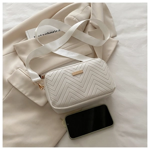 Detailed size comparison of a white quilted crossbody bag next to a smartphone