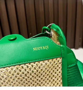 Detail of green leather and straw woven bag with gold logo and silver metal link rings