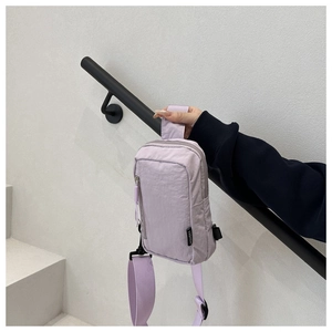 Detail der lavendelfarbenen Brusttasche aus wasserfestem Nylon mit Fashion-Webetikett
