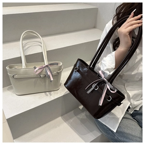 Detailansicht glänzender Ledertaschen mit Metallring-Akzenten und dekorativen Schleifen