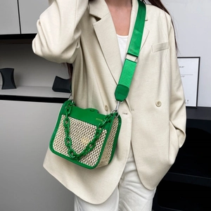 Detail of straw woven crossbody bag featuring green leather trim and acrylic chain