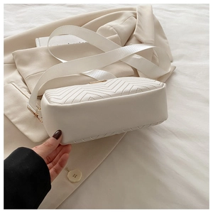 Detail of white chevron quilted PU leather crossbody bag with wide textile strap