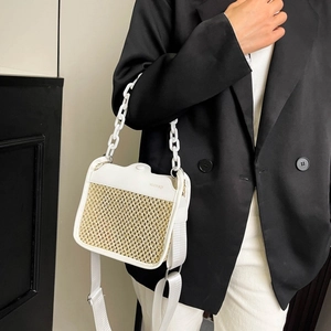 Detail of white straw and leather crossbody bag featuring a chunky chain and brand logo