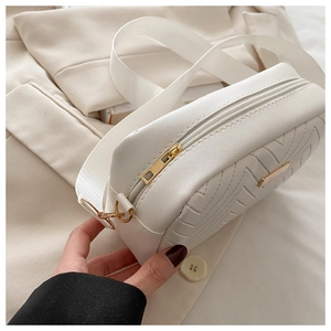 Detail view of white quilted cross-body bag with V-shaped stitching and gold hardware