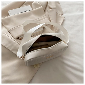 Close-up of white chevron quilted crossbody bag showing interior phone storage space