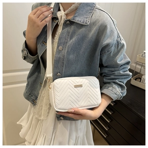 Close-up of white crossbody bag with V-shaped quilting and adjustable canvas strap