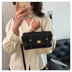 Detail view of black leather handbag with woven flap texture and gold twist-lock closure
