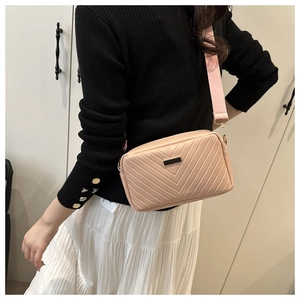 Detailed view of pink crossbody bag with V-quilted texture and wide fabric strap