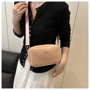 Detail of nude pink quilted crossbody bag with chevron stitching and wide strap