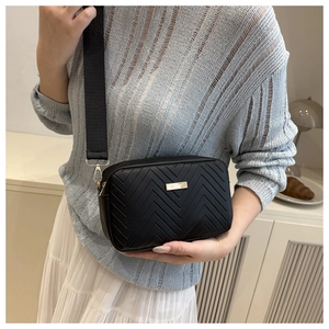 Detail of chevron quilted crossbody bag with golden hardware and wide woven strap