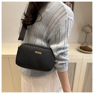 Close-up of black chevron quilted crossbody bag with gold hardware and wide strap