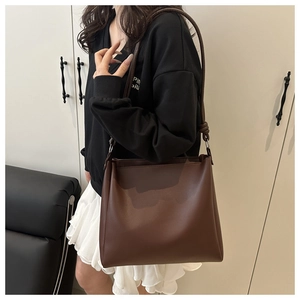 Detail view of large dark brown leather bucket bag with silver metal ring and shoulder strap