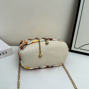 Détail du mini sac seau montrant le fond en tissu imprimé et la chaîne dorée