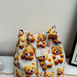 Détail du sac seau avec imprimé d'ours en 3D et bandoulière chaîne dorée