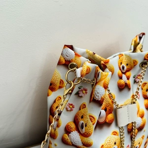 Détail du sac seau imprimé montrant les motifs d'ours en peluche et la chaîne dorée