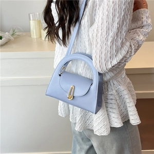 Light blue semi-circular handbag with gold buckle shown on shoulder for daily styling